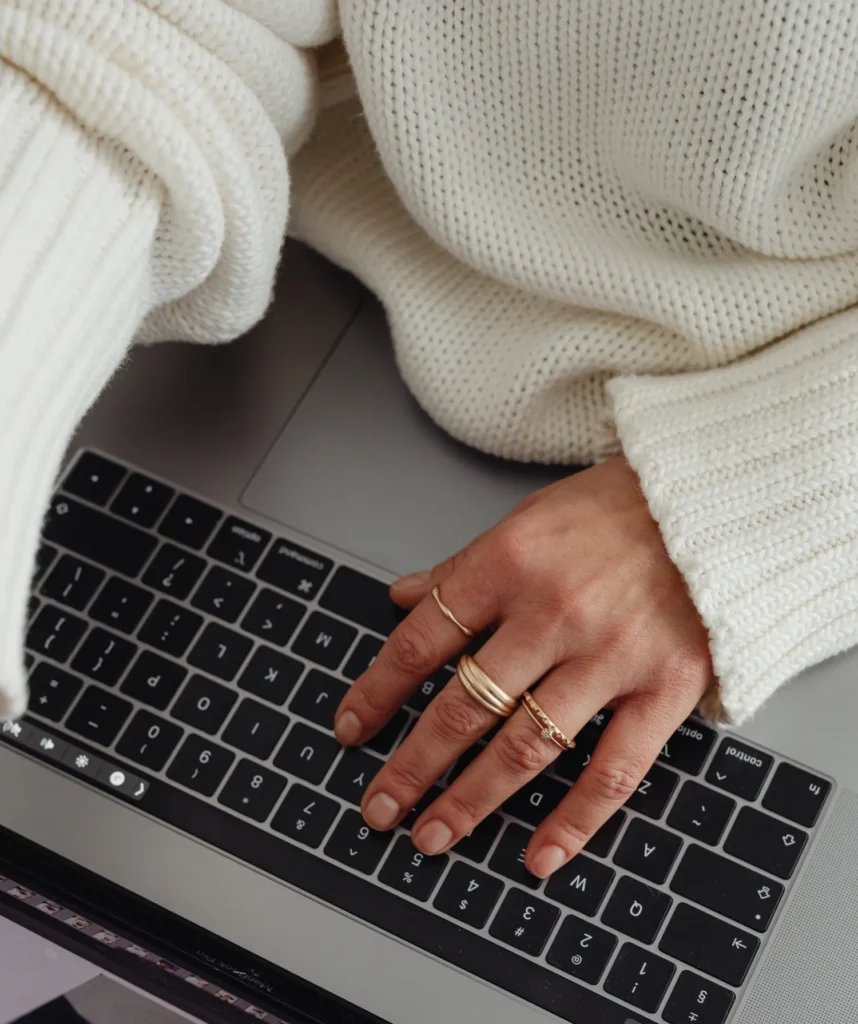 Jegyzetelő kéz laptop billentyűzetén, online konzultáció közbeni munka részlete
